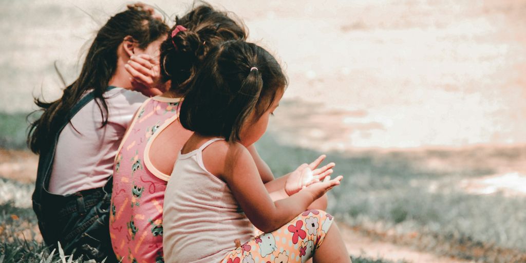 three children sitting on grass