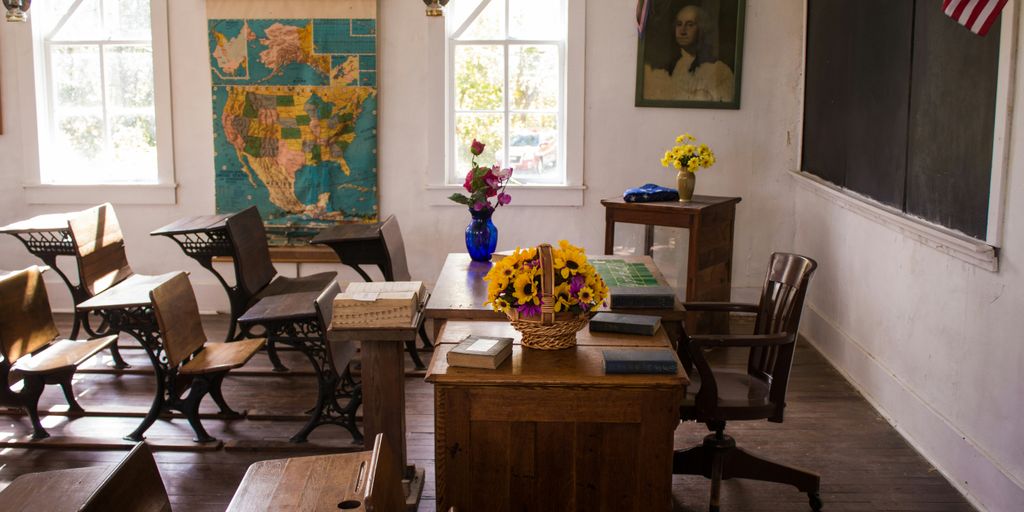 vacant white painted classroom with chairs, tables , and map on the wall